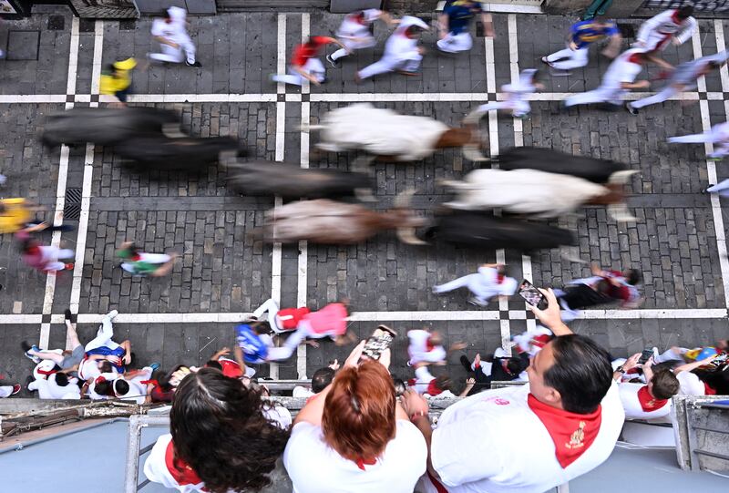 Spectators watch from a balcony as participants run during the eigth running of the bulls of the San Fermín festival in Pamplona, northern Spain, last July. Photograph: Ander Gillenea/AFP via Getty Images