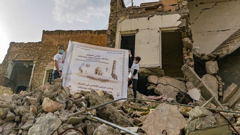 Youths unfurl a poster welcoming Pope Francis above the rubble of a destroyed house next to the ruins of the Syriac-Catholic Church of the Immaculate Conception (al-Tahira) in the old city of Iraq’s northern city of Mosul in March. Photograph: Zaid al-Obeidi/AFP via Getty Images
