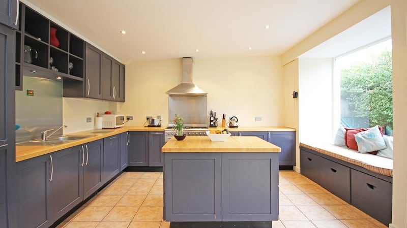 The kitchen at 28 Curzon Street, Dublin 8 has grey-painted kitchen units,   wooden countertops and a  Smeg cooker with a five-ring gas hob