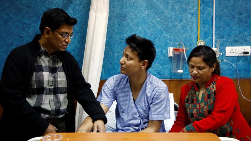 Sanam Shakya (33), a survivor of the US-Bangla plane crash,  with his parents while undergoing treatment at a hospital in Kathmandu, Nepal. Photograph: Navesh Chitrakar/Reuters