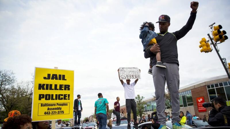 Demonstrators stand on top of vehicles at the intersection of North Avenue and Pennsylvania Avenue in Baltimore. Baltimore residents cautiously celebrated news on Friday that six police officers involved in the arrest of Freddie Gray face criminal charges. Photograph: Eric Thayer/EPA
