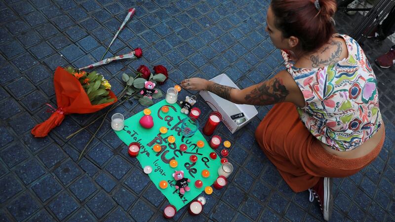 A woman places a candle on a placard, reading in Spanish and Catalan ‘Catalonia, place of peace’, in the area where a van crashed into pedestrians at Las Ramblas street in Barcelona. Photograph: Reuters