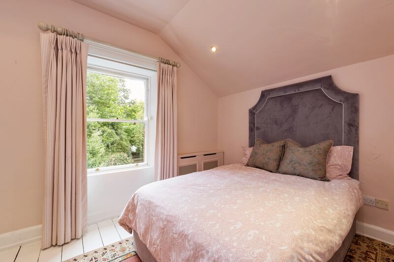 Second bedroom with sash window and painted floorboards.