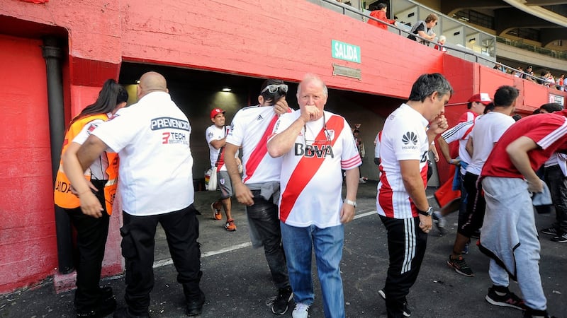 Supporters of River Plate cover their faces after being affected by pepper gas sprayed by police outside the Monumental stadium in Buenos Aires. Photograph: Javier Gonzalez/Toledo/AFP/Getty Images