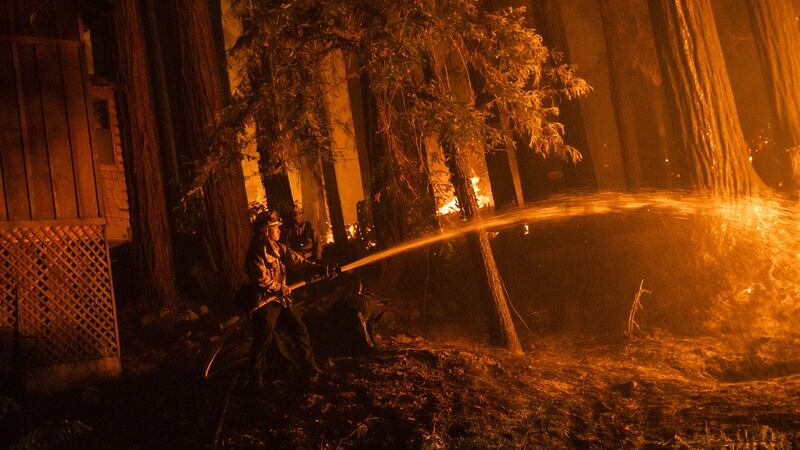A firefighter  protects a home as flames approach  in Santa Cruz County, California, on Thursday. Photograph: Philip Pacheco/Bloomberg