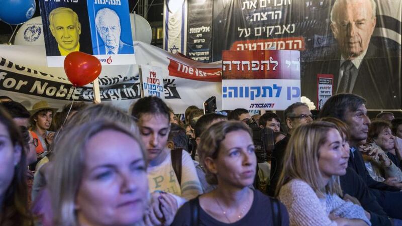 A demonstrator holds a placard bearing an image of Israeli Prime Minister Benjamin Netanyahu and the word “cowardice” in Hebrew next to an image of Israel’s late prime minister Yitzhak Rabin bearing the word “leadership” at a rally in Tel Aviv on Saturday. Photograph: AFP/Getty Images/Jack Guez