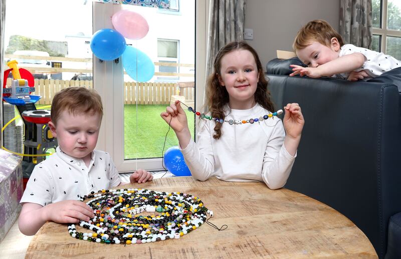 Alex Burke sorts his collection of beads as Kayla and Dylan look on. Photograph: Joe O'Shaughnessy