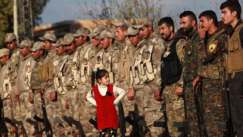 A young girl stands in front of fighters from the Syrian Democratic Forces in the Kurdish-controlled city of Qamishly in northeastern Syria, on December 3rd. They were attending  the funeral of a fellow fighter killed in the town of Hajin during battles against the Islamic State terror group. Photograph: Delil Souleiman/AFP/Getty Images