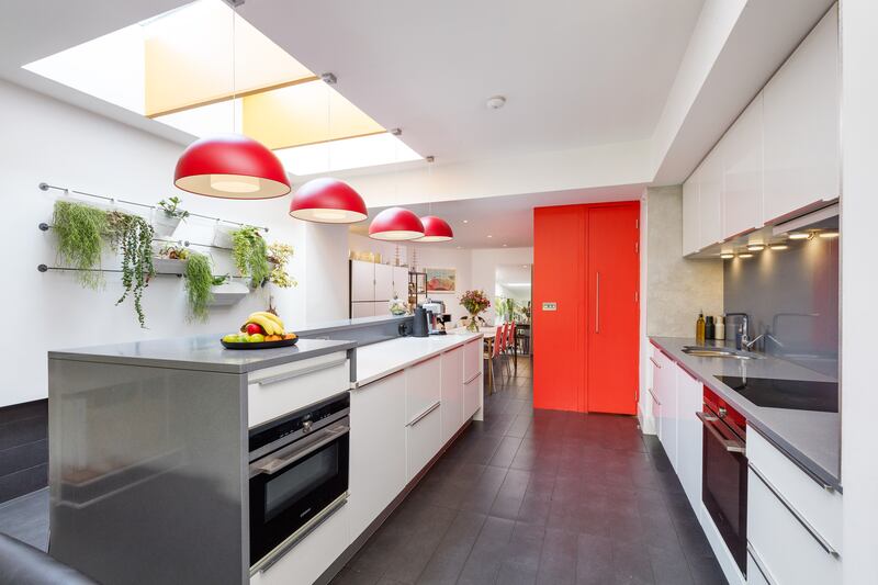The kitchen has sleek white units with a huge central island/breakfast bar