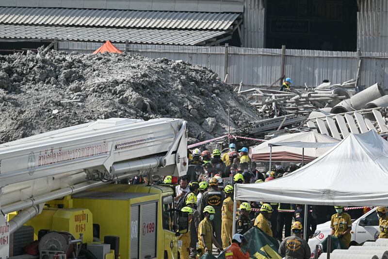 Myanmar and Thailand earthquake: Rescue workers stand near the debris of a construction site after a building collapsed in Bangkok. Photograph: Lillian Suwanrumpha/AFP