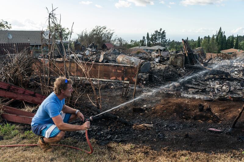 Andre Fehlmann sprays water on hot spots in the area where his home stood before being destroyed by a wildfire in Kula, Maui, Hawaii. Photograph: Go Nakamura/New York Times
