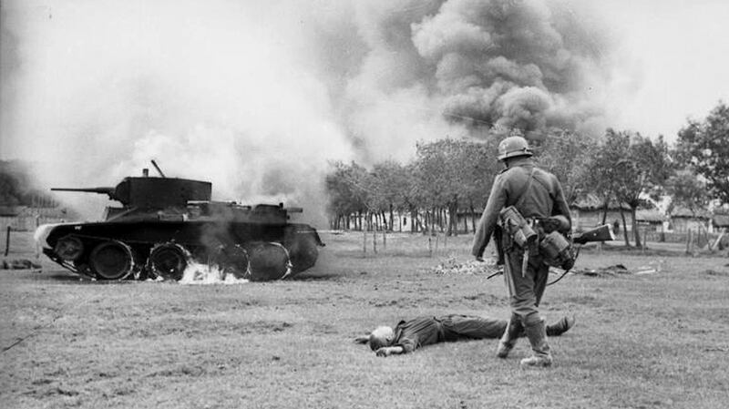A German infantryman walks toward the body of a killed Soviet soldier and a burning BT-7 light tank in the southern Soviet Union in in 1941, during the early days of Operation Barbarossa. Photograph: Deutsches Bundesarchiv/German Federal Archive
