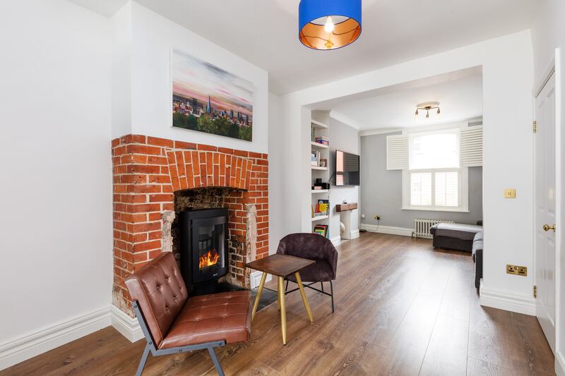 A contemporary stove sits in an old hearth in what was the second room downstairs