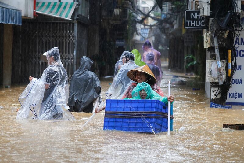 Local residents with their goods wade through the flood waters in Hanoi on Wednesday. Photograph: Luong Thai Linh/EPA