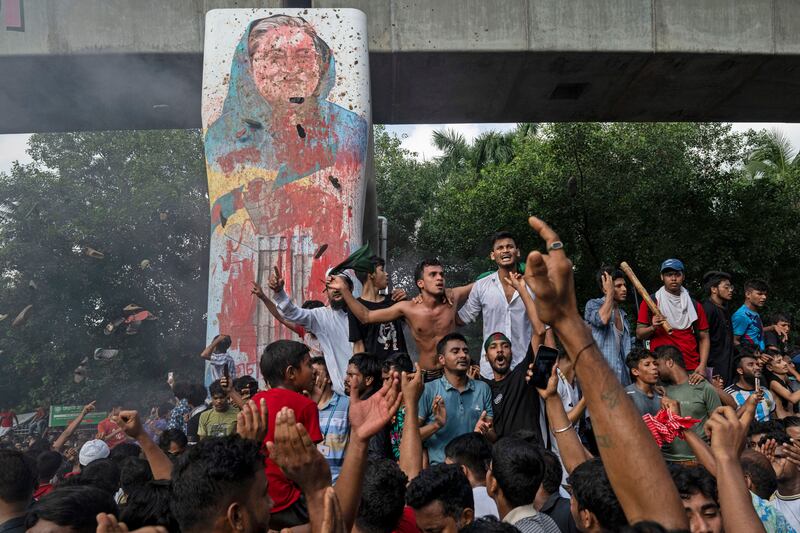 Protesters in Dhaka celebrate beside a defaced portrait of former prime minister Sheikh Hasina after news of her resignation. Photograph: Fatima Tuj Johora/AP