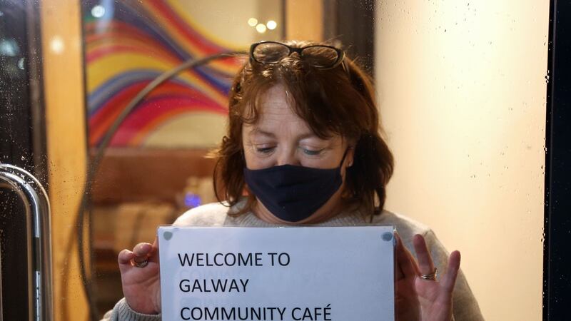 Galway Community Cafe: Geraldine O’Connor, Peer Connector, placing a temporary sign inside the door at the entrance to the cafe before opening. Photograph: Joe O’Shaughnessy.