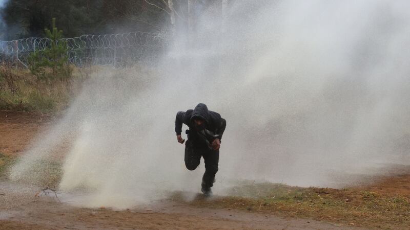 A man runs away from a water cannon used by Polish law enforcement officers against migrants. Photograph: Leonid Shcheglov/Belta/AFP via Getty