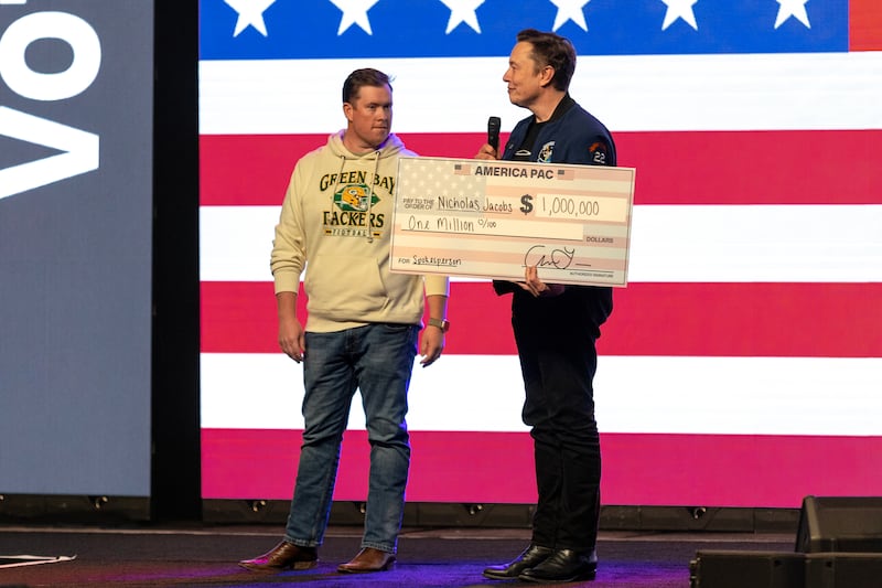 Elon Musk presents a cheque for $1 million to sweepstakes winner Nicholas Jacobs at a rally in support of Brad Schimel's candidacy for the Wisconsin supreme court. Photograph: Jim Vondruska/New York Times
                      