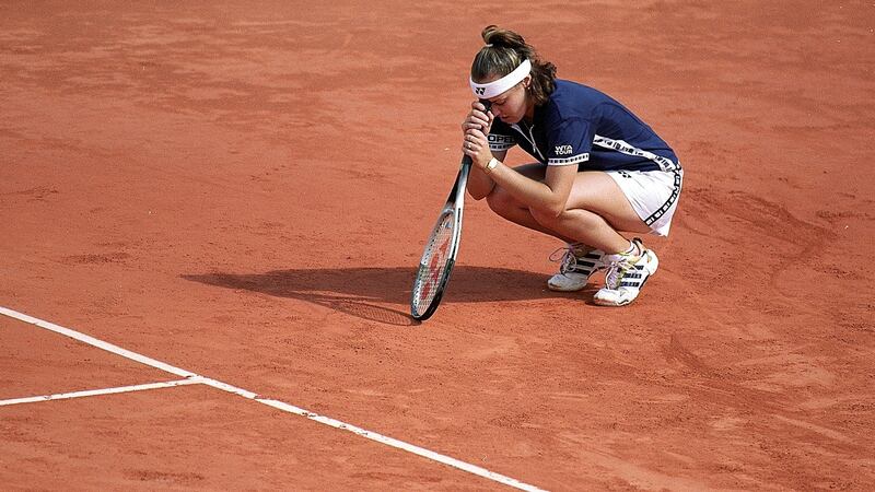 Martina Hingis  looks dejected as she leans her head on her racket after losing the second set in her women’s final match to Steffi Graf  in the 1999 French Open.