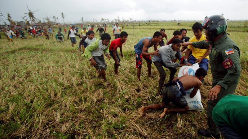 A Philippine Air Force personnel officer tries to push away survivors of Typhoon Haiyan from the moving rotor of a helicopter, as its crew deploys aid into a remote area some 25km west of Tacloban city today. Photograph: Wolfgang Rattay/Reuters