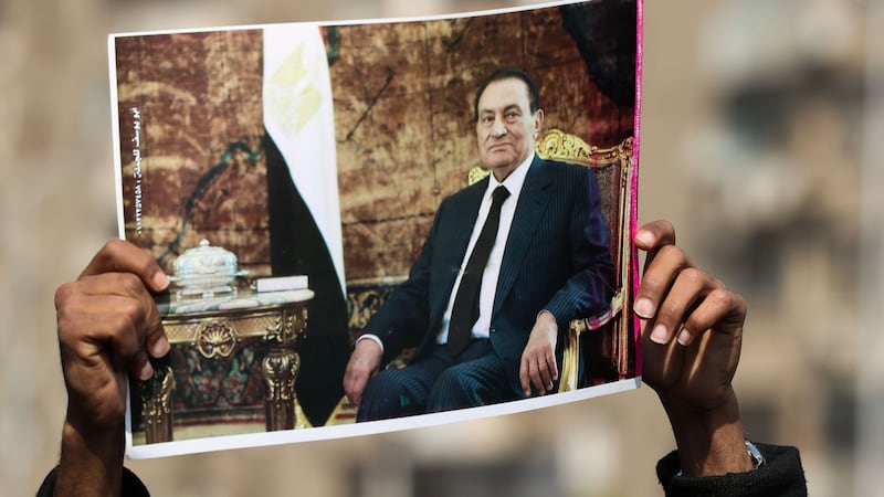 A supporter of Hosni Mubarak lifts a picture of the late leader near the family cemetary in Cairo. Photograph:   Mohamed El-Shahed/AFP via Getty Images