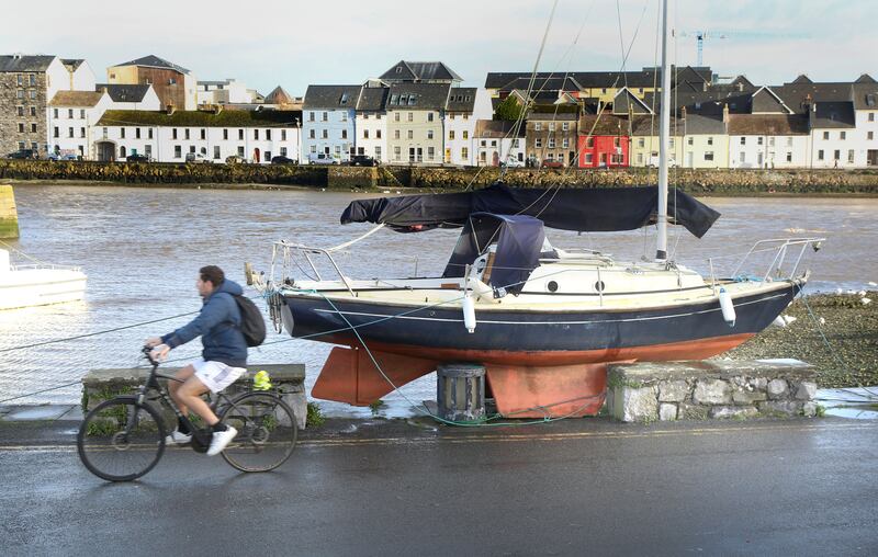 A man cycles past of marooned boat at Nimos Pier after it was lifted by the high tide and waves during Storm Debi in Galway. Photograph: Joe O'Shaughnessy