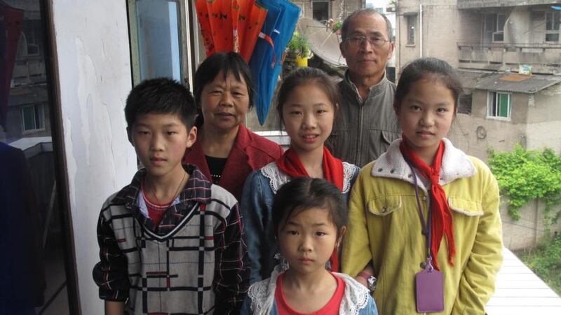 Liu Qiti and his family in Hechuan: Liu, a 68-year-old motorbike courier, is enormously proud of his two granddaughters, aged 11 and 7.  Photograph:  Clifford Coonan