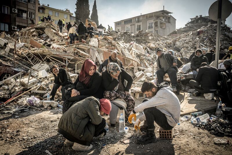 Displaced residents sit near their collapsed home as rescue operations continue in Antakya, Turkey. Photograph: Sergey Ponomarev/The New York Times