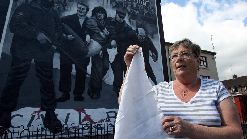 Kay Duudy, the sister of Jackie Duddy who was shot dead on Bloody Sunday, standing in front of a mural depicting the moment her brother was led away from danger by Edward Daly as she holds the white handkerchief that Dr Daly waved as he did so. Photograph: Paul Faith/PA Wire
