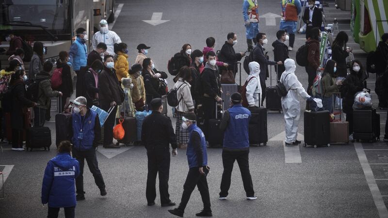 Chinese workers and health officials wear protective gear as they gather to take buses while being processed and taken to do 14 days of quarantine, after arriving by train  in Beijing, China. Photograph: Kevin Frayer/Getty Images