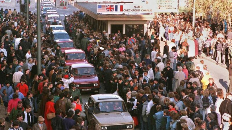 A long row of East German Trabant cars passing through Checkpoint Charlie into West Berlin is greeted by enthusiastic West Berliners, on November 10th,  1989