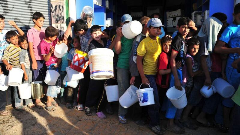Boys carry buckets as they queue to receive free food for their first iftar, or breaking fast, during the Muslim fasting month of Ramadan in Raqqa province, eastern Syria. Photograph: Nour Fourat/Reuters