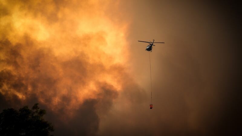 Helicopters dump water on bushfires as they approach homes located on the outskirts of of Bargo on Saturday. Photograph: David Gray/Getty