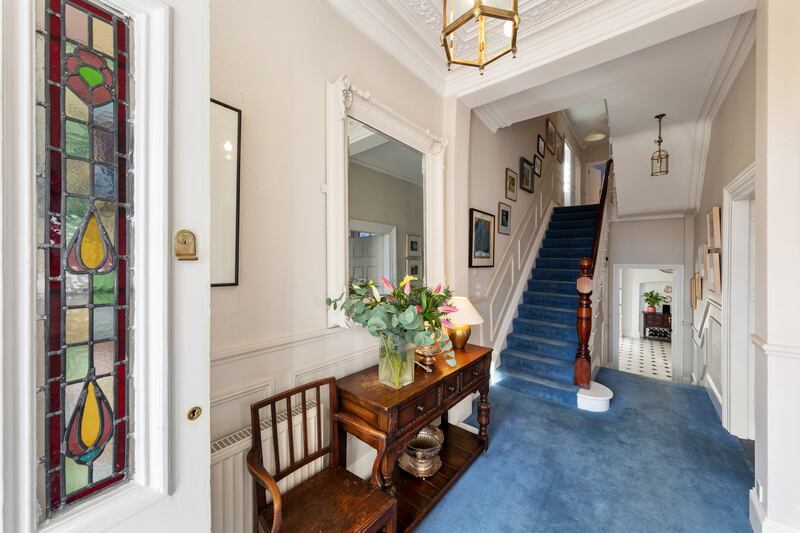 The front door has stained glass panes and its colour shines through into the bright entrance hallway