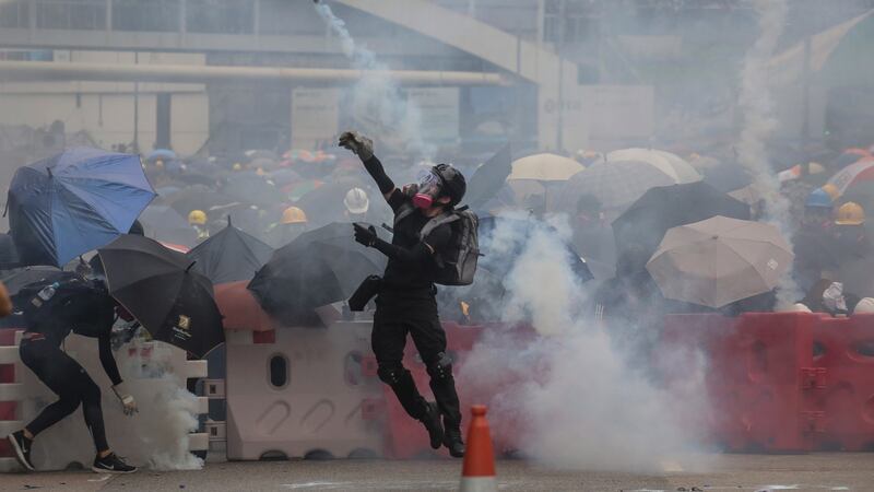 A protester (centre) wearing a gas mask throws tear gas back after police fired tear gas during an anti-government rally in Hong Kong, on Saturday. Photograph: EPA