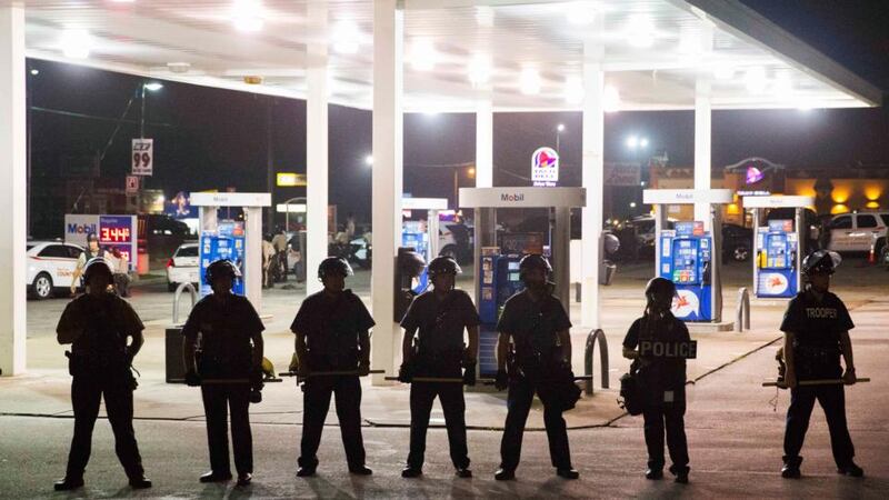 Police officers stand guard at a petrol station last night after protests against the shooting of Michael Brown  in Ferguson, Missouri. Photograph:  Lucas Jackson/Reuters.