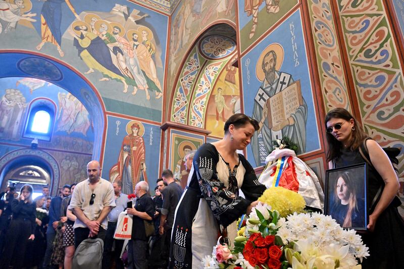 A young woman lays flowers near the coffin of Victoria Amelina, 37, during her funeral service in Mykhaylo Gold Domes in Kyiv on July 4th, 2023. The Ukrainian writer and war crimes investigator was fatally wounded in a Russian missile strike last week on the Ria Pizza restaurant in Kramatorsk on Tuesday. Photograph: SERGEI SUPINSKY/AFP via Getty Images