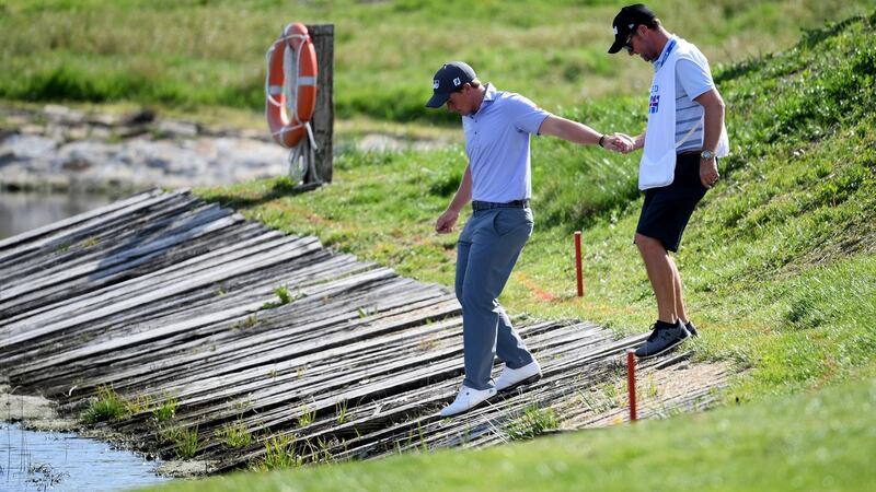 Dunne of Ireland is held by his caddie Darren Reynolds as he looks for his ball in the water at the 17th. Photo: Ross Kinnaird/Getty Images