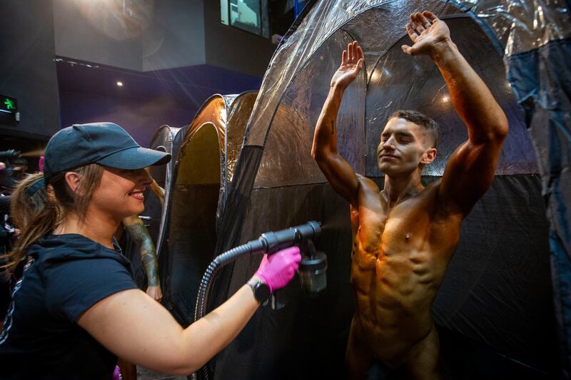 Sarah Desmond applies a spray tan to competitor Callum Roche. Photograph: Tom Honan