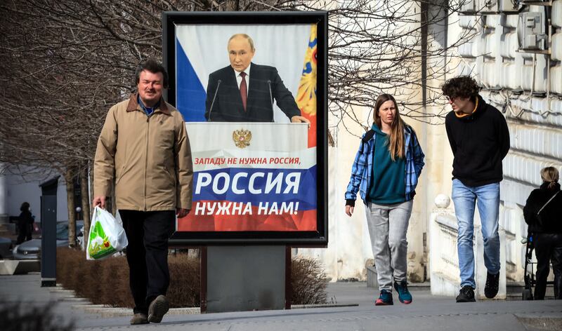 People walk in front of a poster of Russian president Vladimir Putin in Simferopol, Crimea, in March 2024. Photograph: AFP via Getty Images