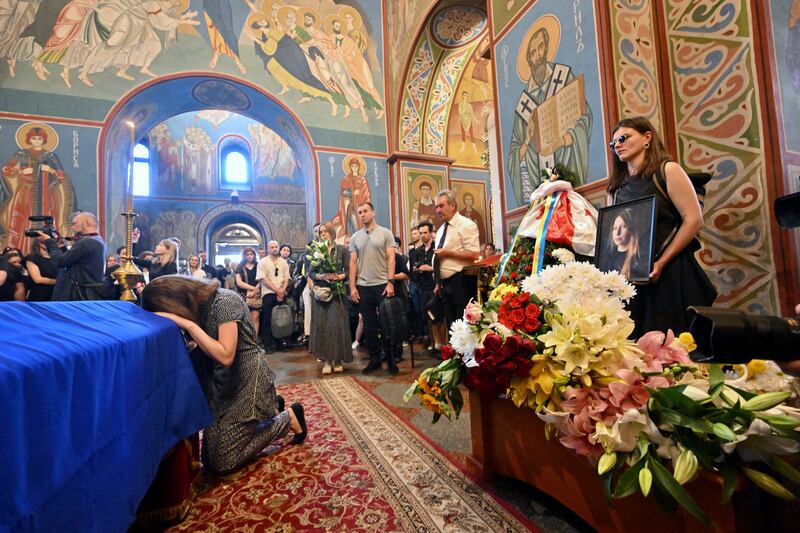 A woman kneels in front of the coffin of Victoria Amelina during her funeral service at Mykhaylo Gold Domes monastery, Kyiv, Ukraine, July 4th, 2023. Photograph: Sergei Supinsky/AFP/Getty